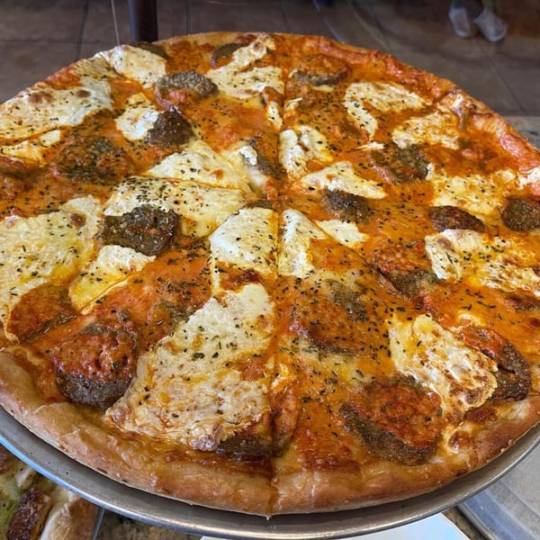 A large, freshly baked Luigi's Pizza with tomato sauce, melted mozzarella, and sausage crumbles.
