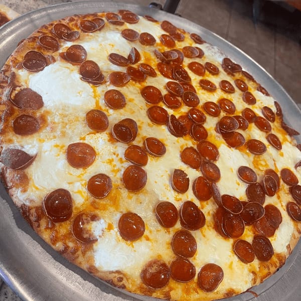 Luigi's Pizza pepperoni pizza, with melted cheese and crispy pepperoni on a metal tray.